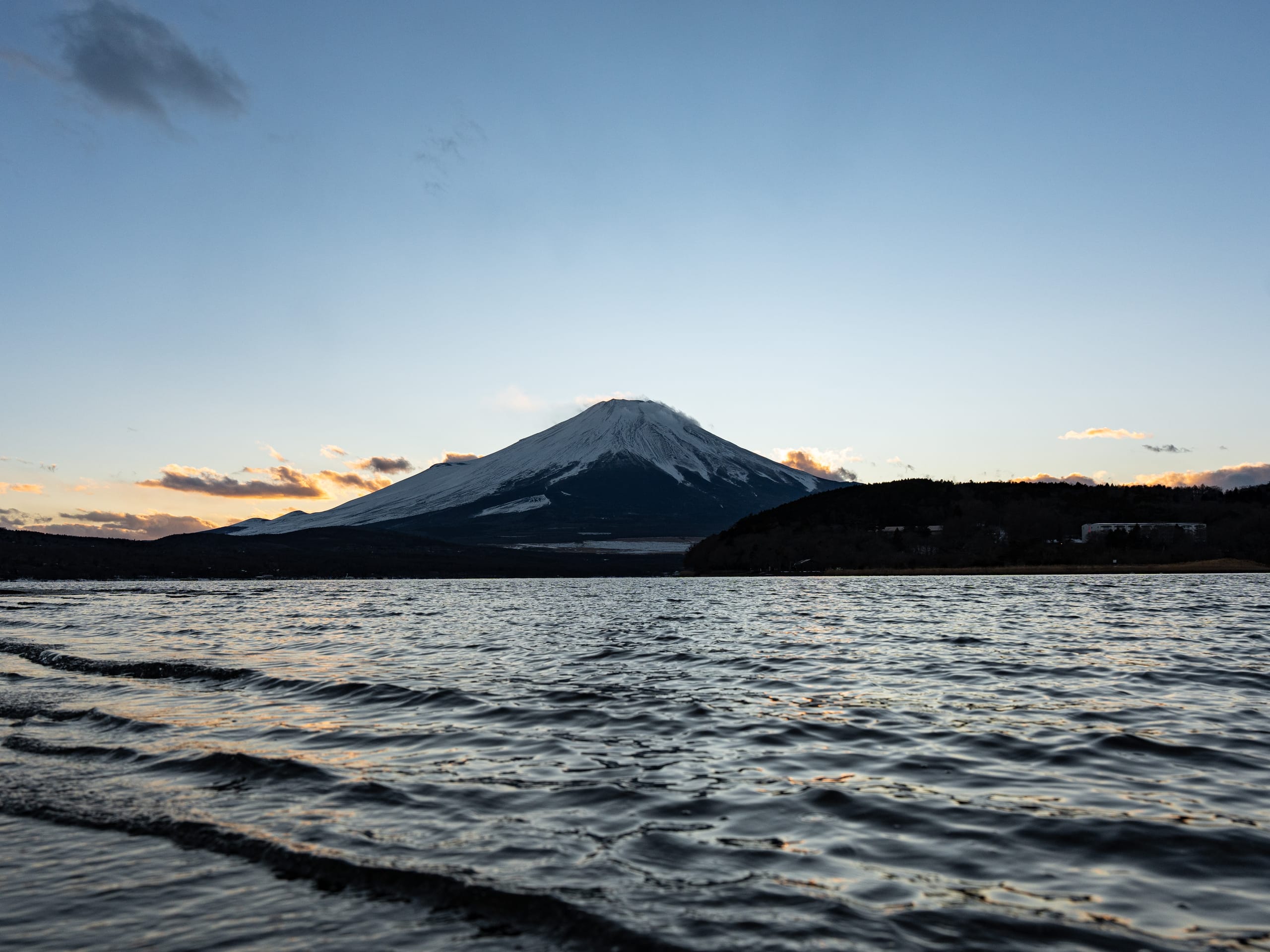 暮色中覆雪山峰横在起伏湖面后方。