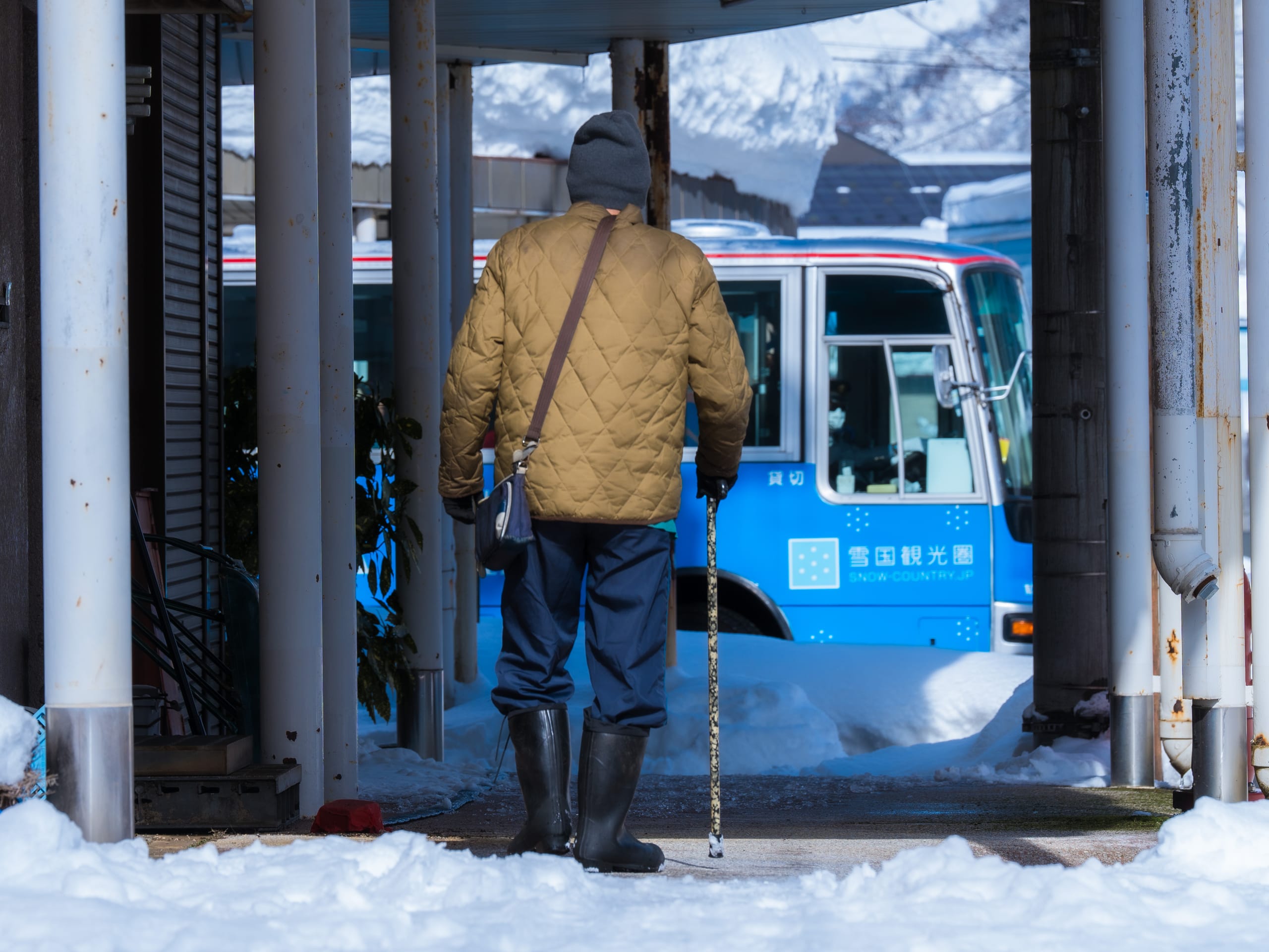 一人穿过积雪站台走向停靠的蓝色电车。