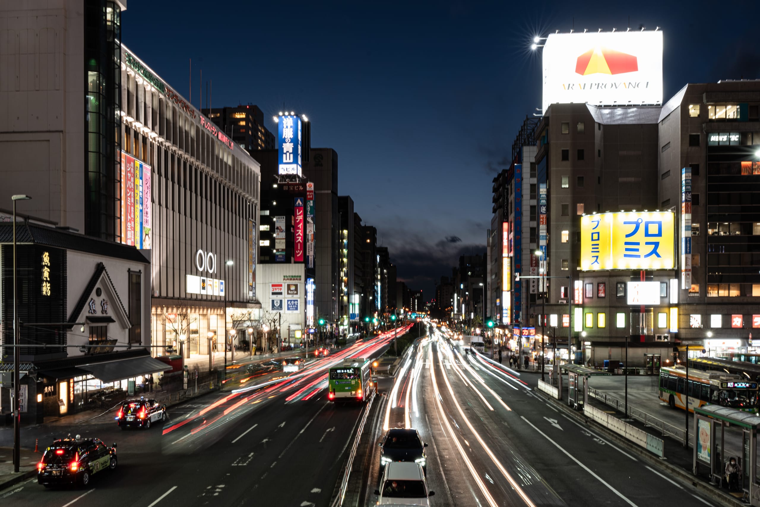 夜间城市主路上，车灯形成连续红白光轨。