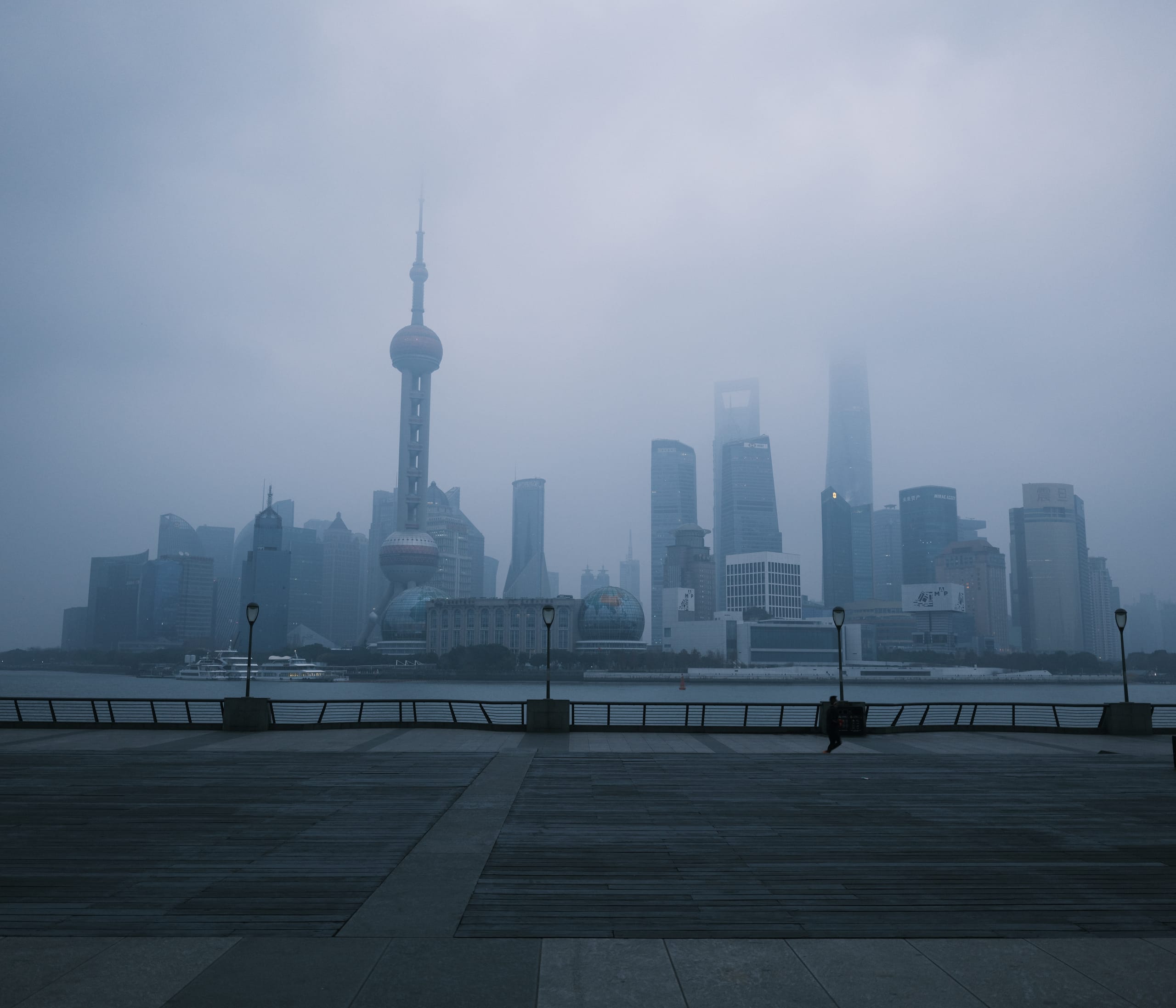 雾气笼罩的滨水城市天际线，远处高楼轮廓若隐若现。