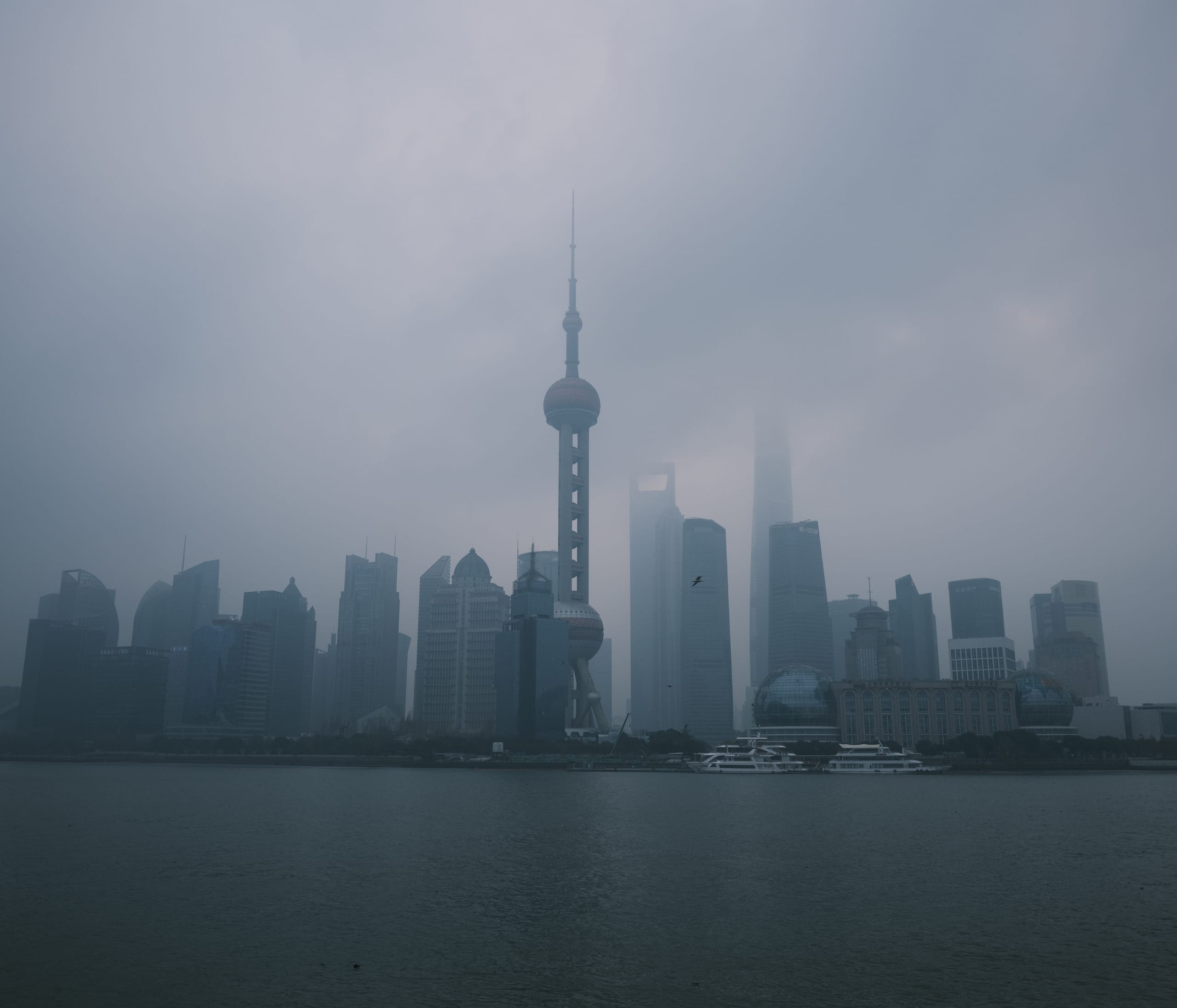隔水望见被浓雾包围的城市高楼与塔楼。