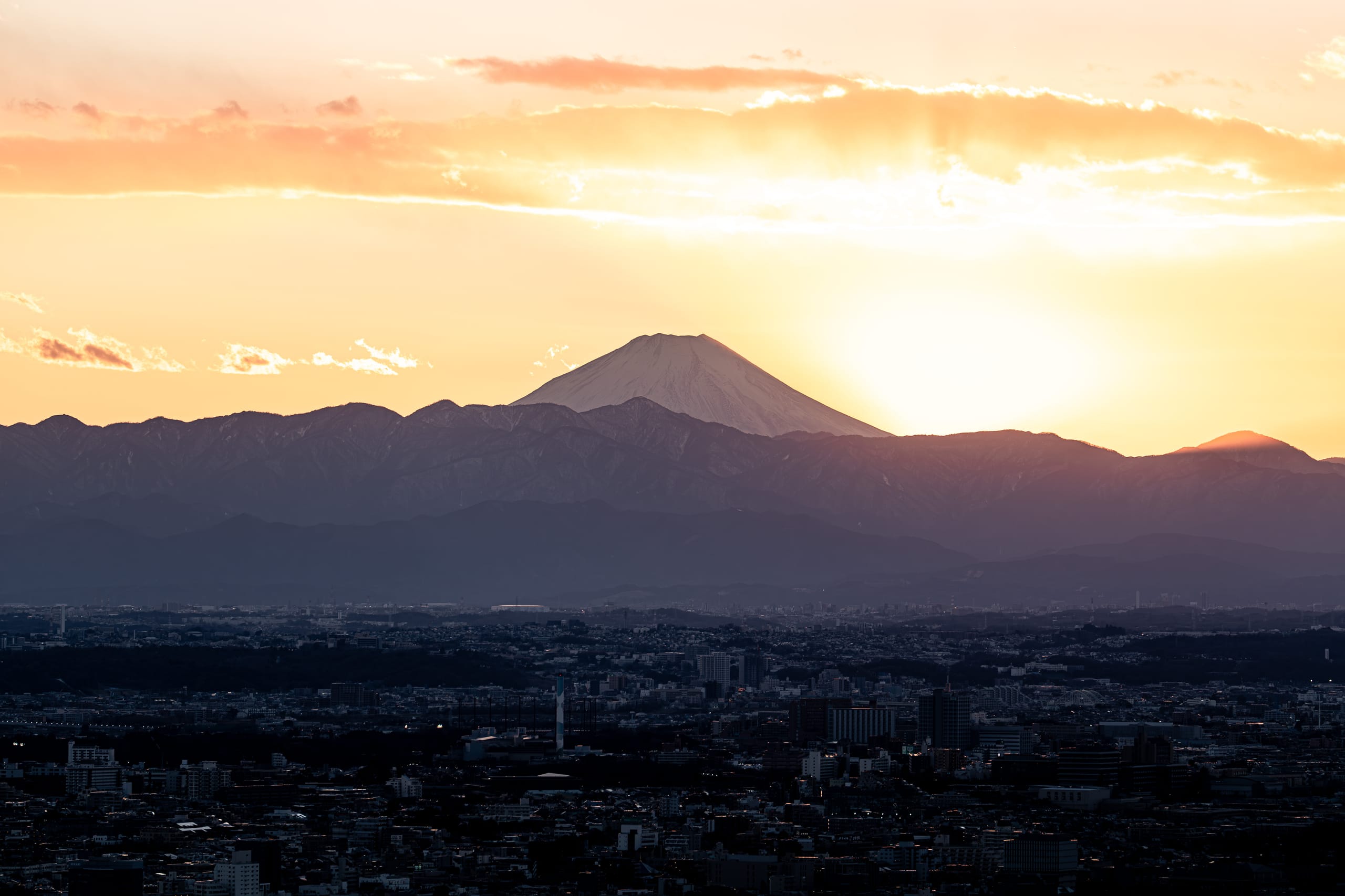 落日从山峰旁沉下，将天空染成金黄色。