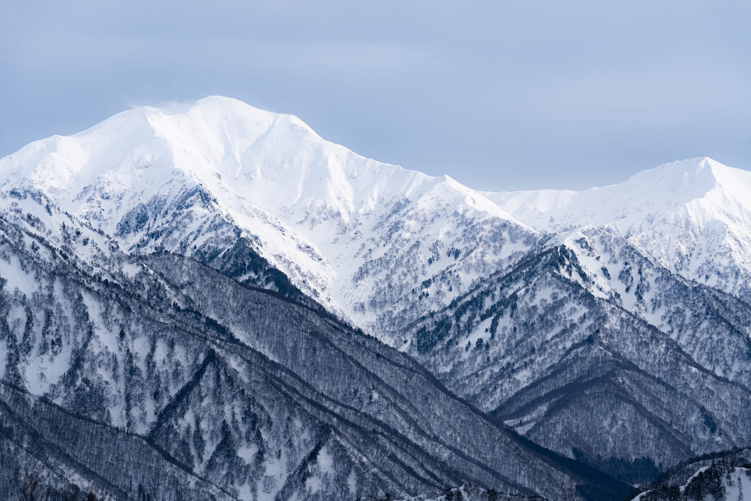 覆雪群峰层层延伸，山脊在阴影和亮光间交错。