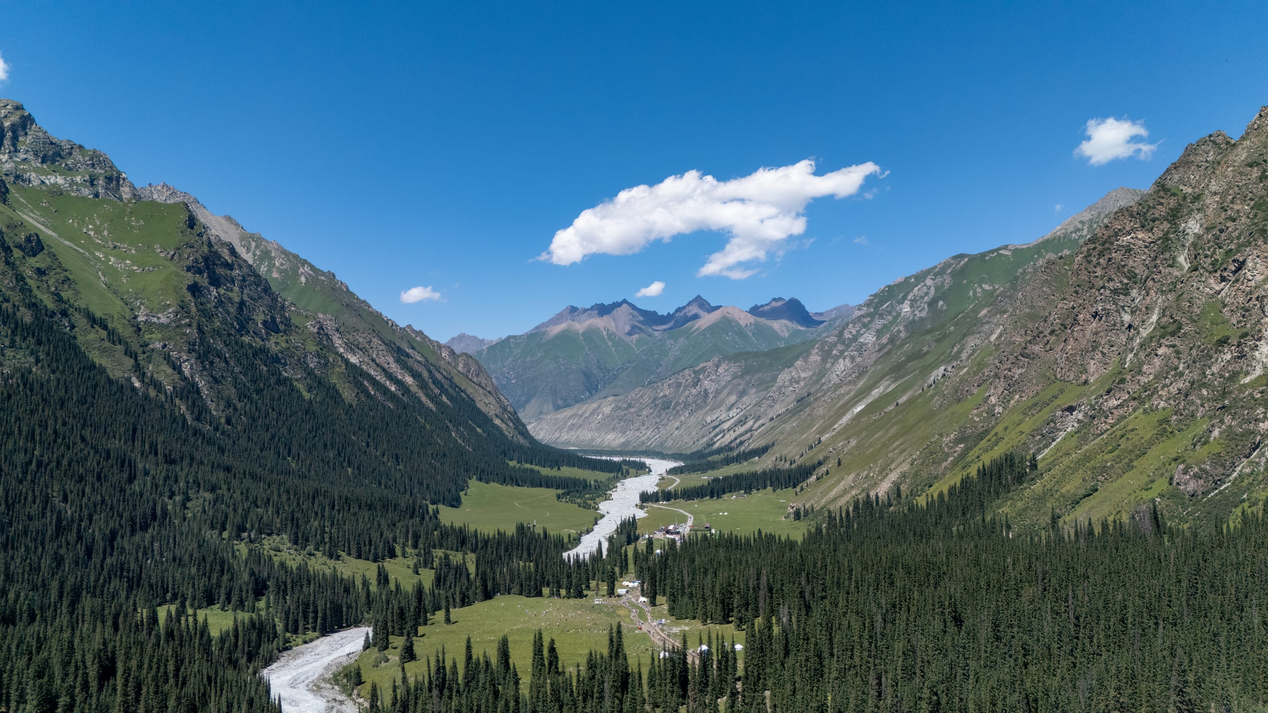 夏塔雪山背面的尖峰与绿色山脊围成山谷，河流和道路在谷底并行。