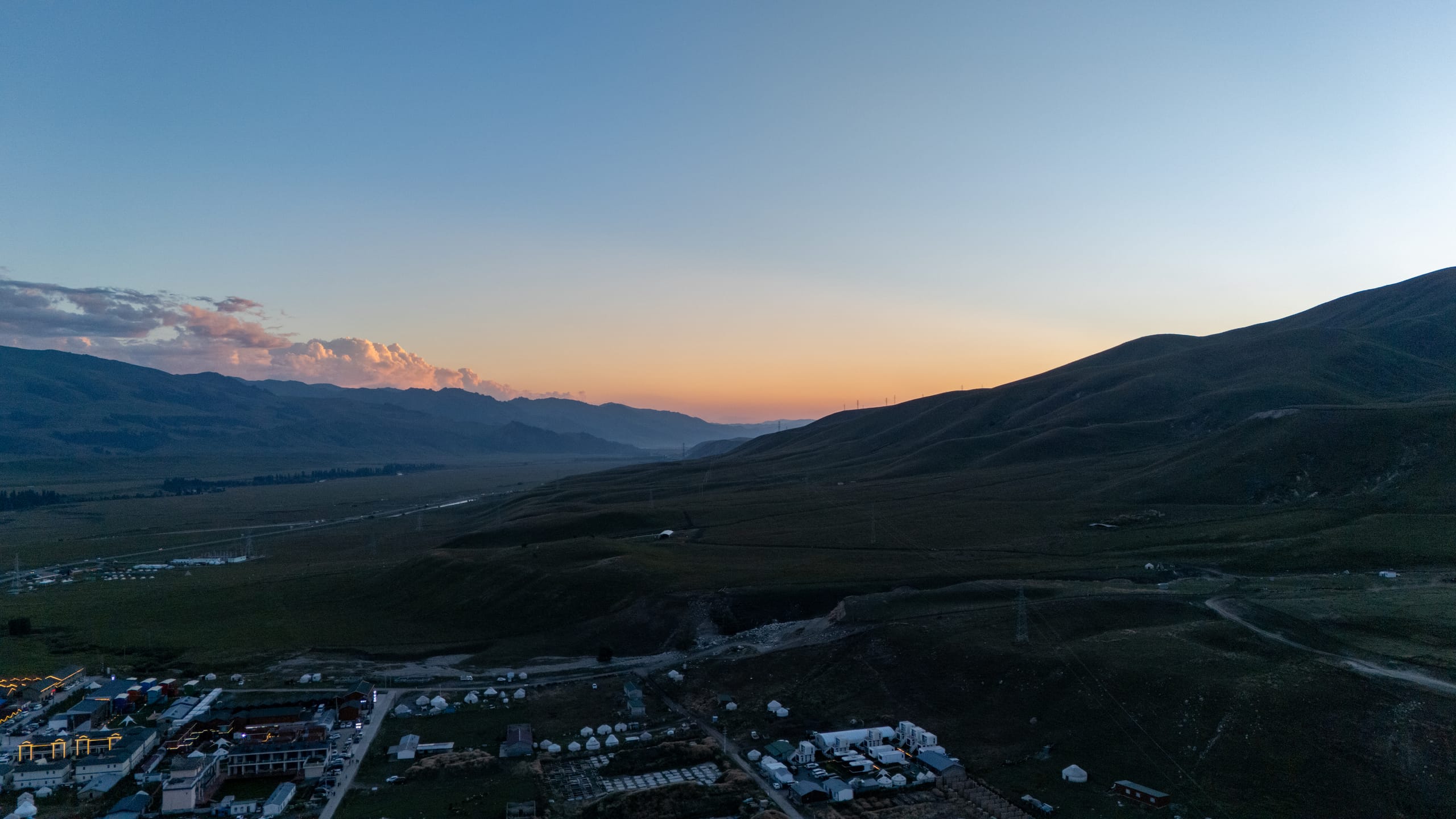 独库公路北段起点附近的山地进入暮色，地平线泛着橙红余晖。