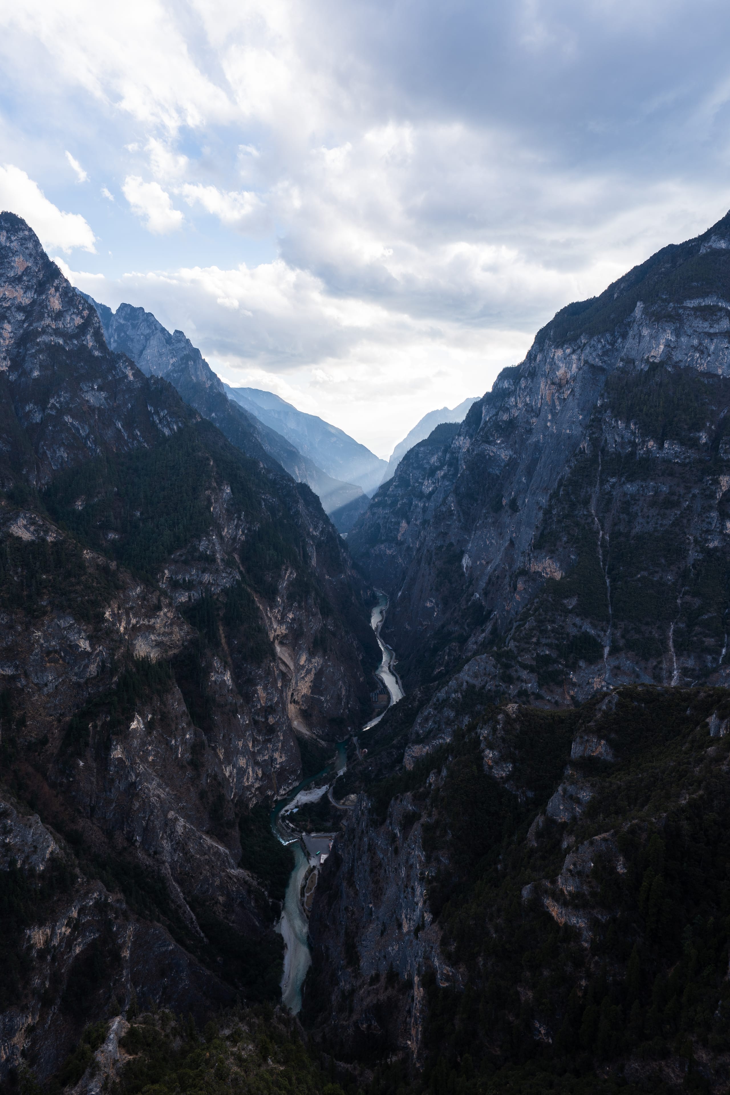 光束穿过云层洒向香格里拉大峡谷，在重叠山峰间形成明暗层次。