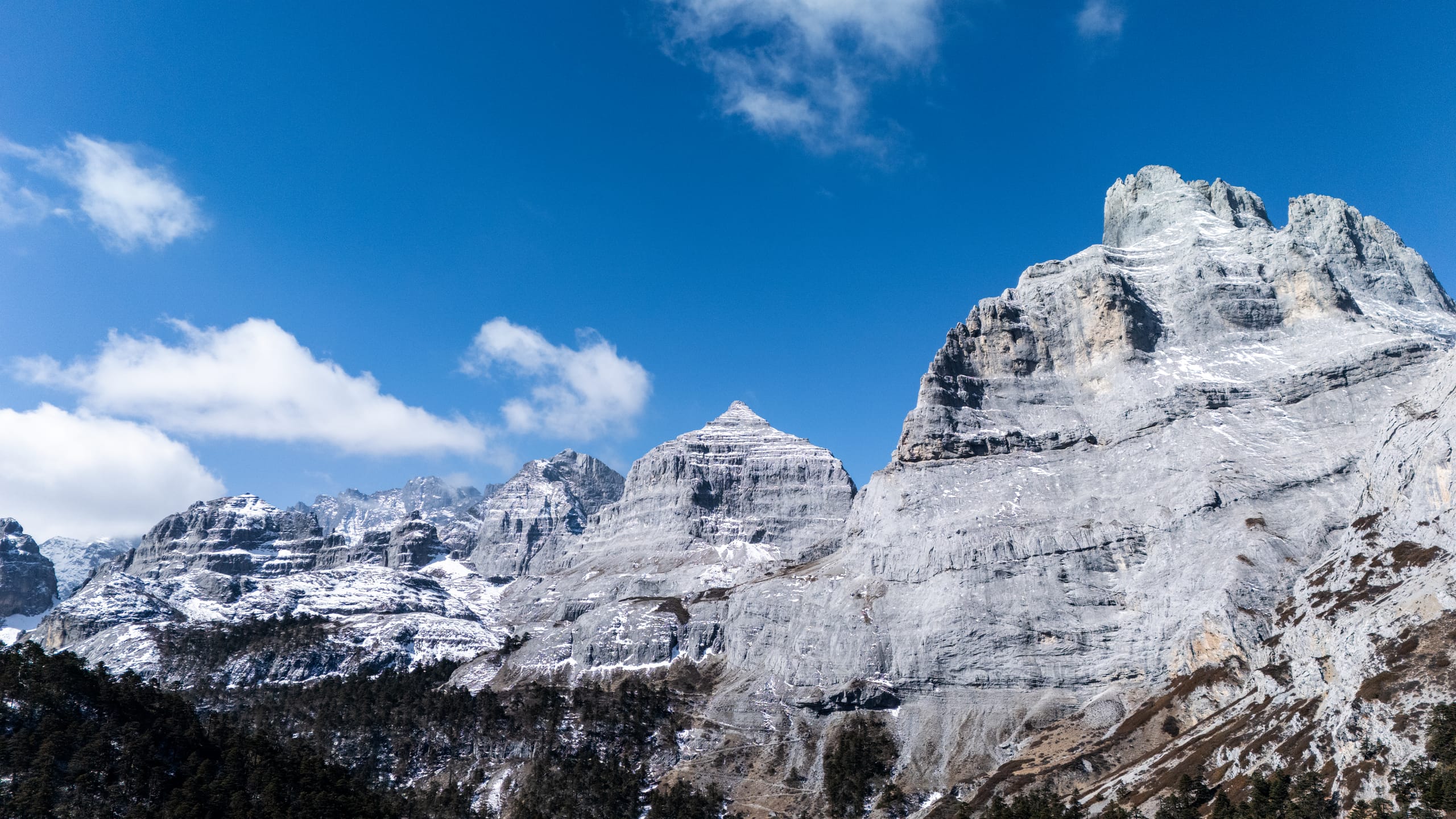 香巴拉佛塔白色峰体近景，阶梯状岩层与积雪在蓝天下清晰可见。
