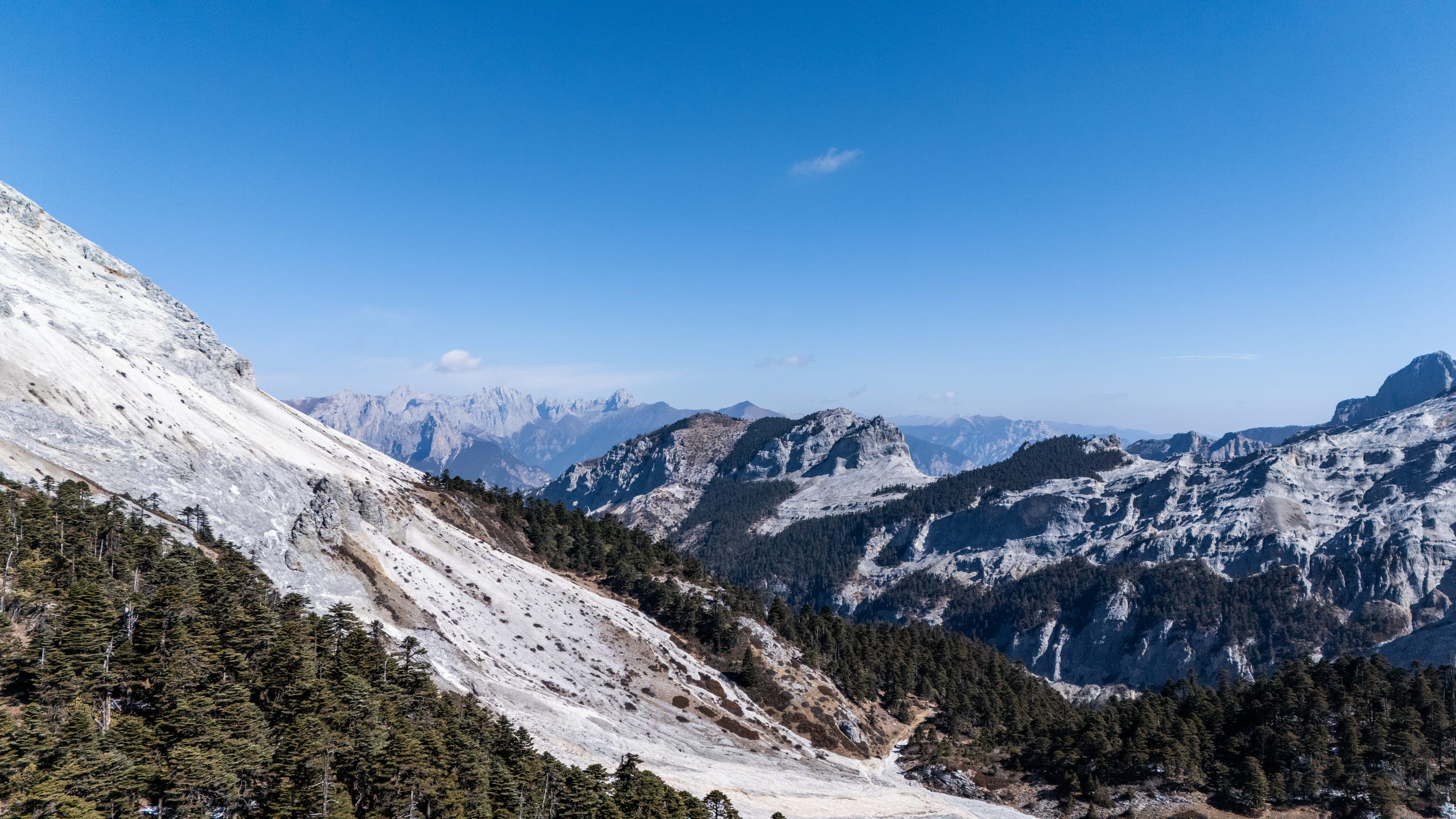 从雪坡侧望香巴拉佛塔周边群山，层叠雪峰延伸至远方。
