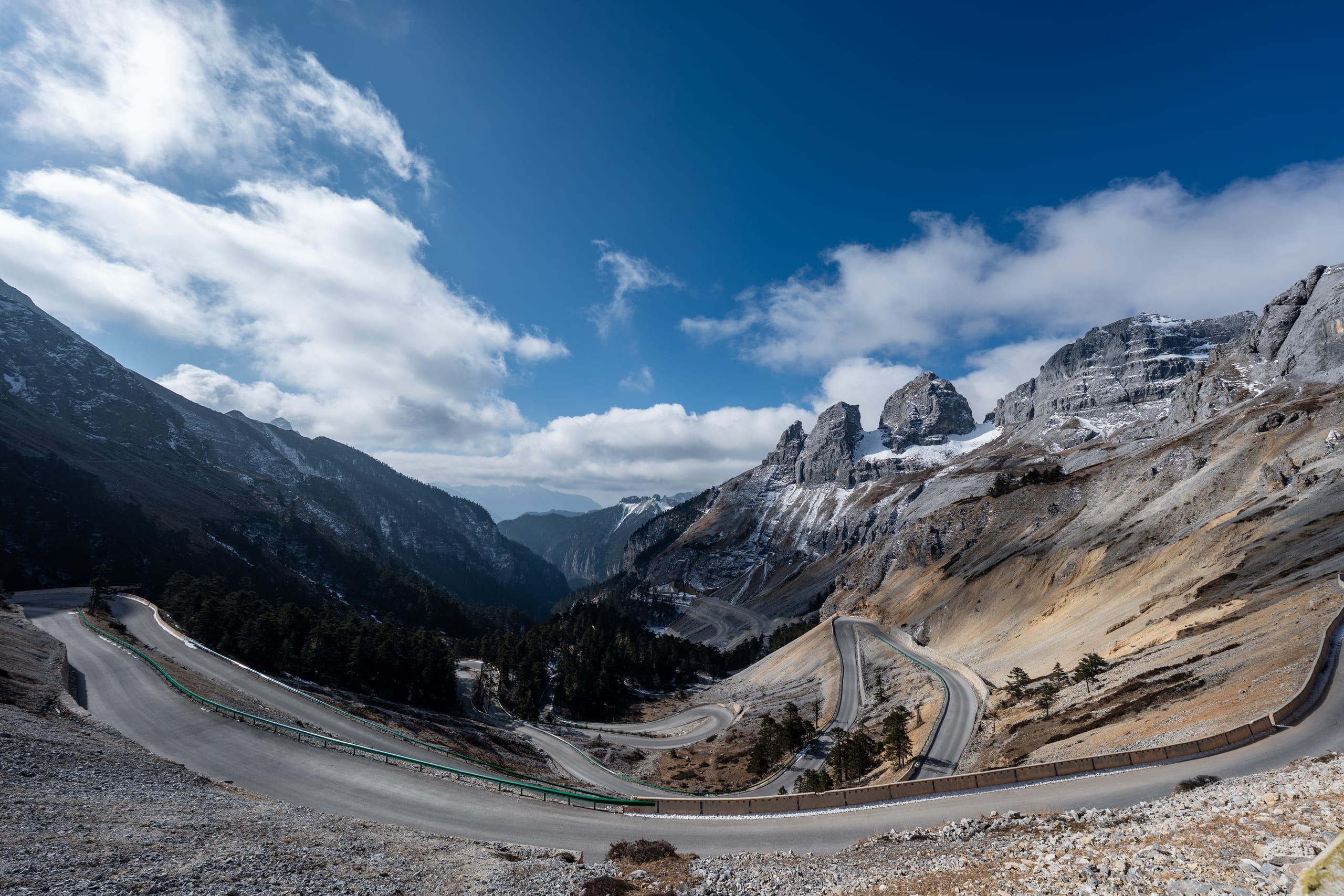 通往香巴拉佛塔的道路在雪山之间迂回，沿裸露山坡向谷底延伸。