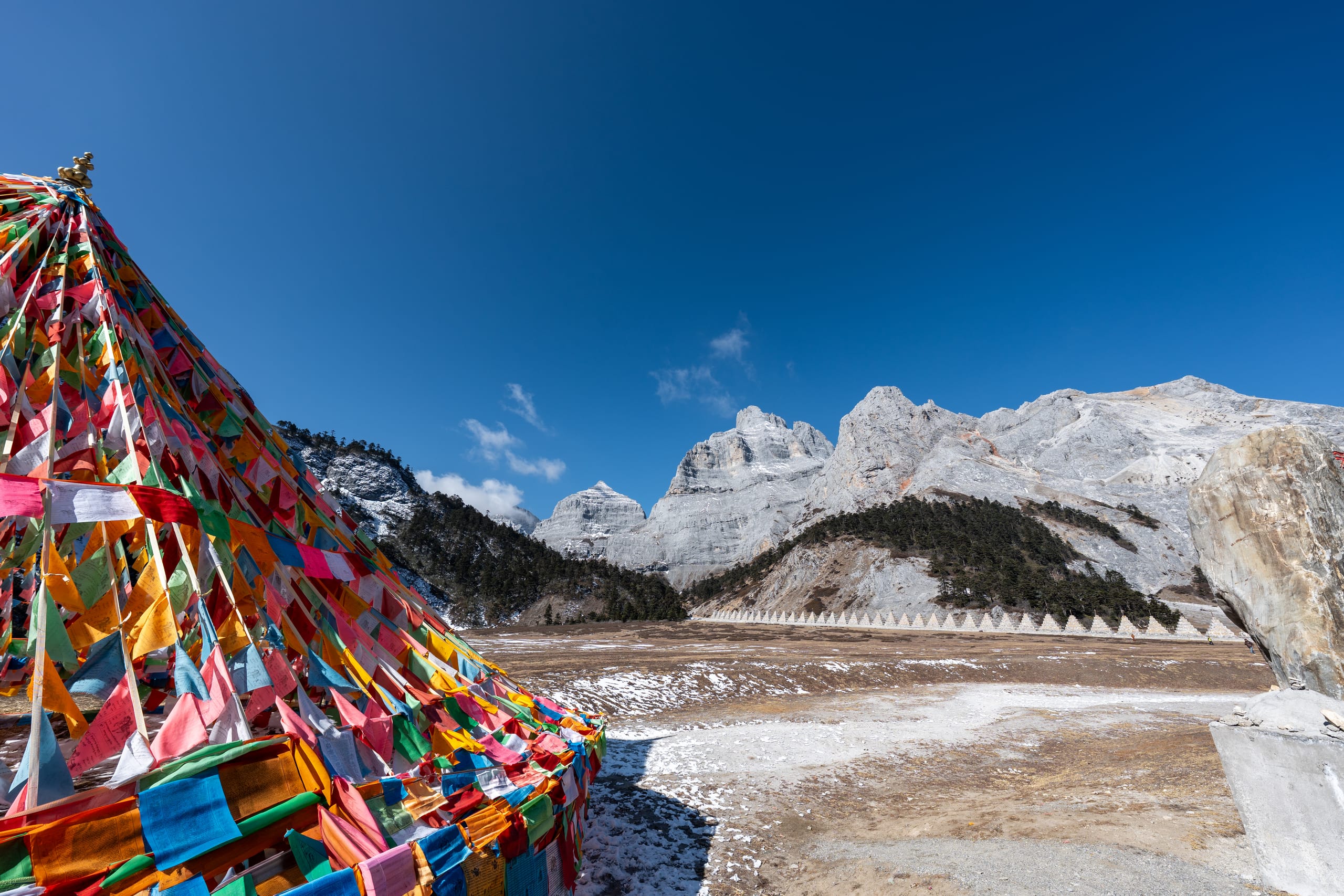 密集彩色经幡在香巴拉佛塔雪山前组成锥形，经幡随风交叠。
