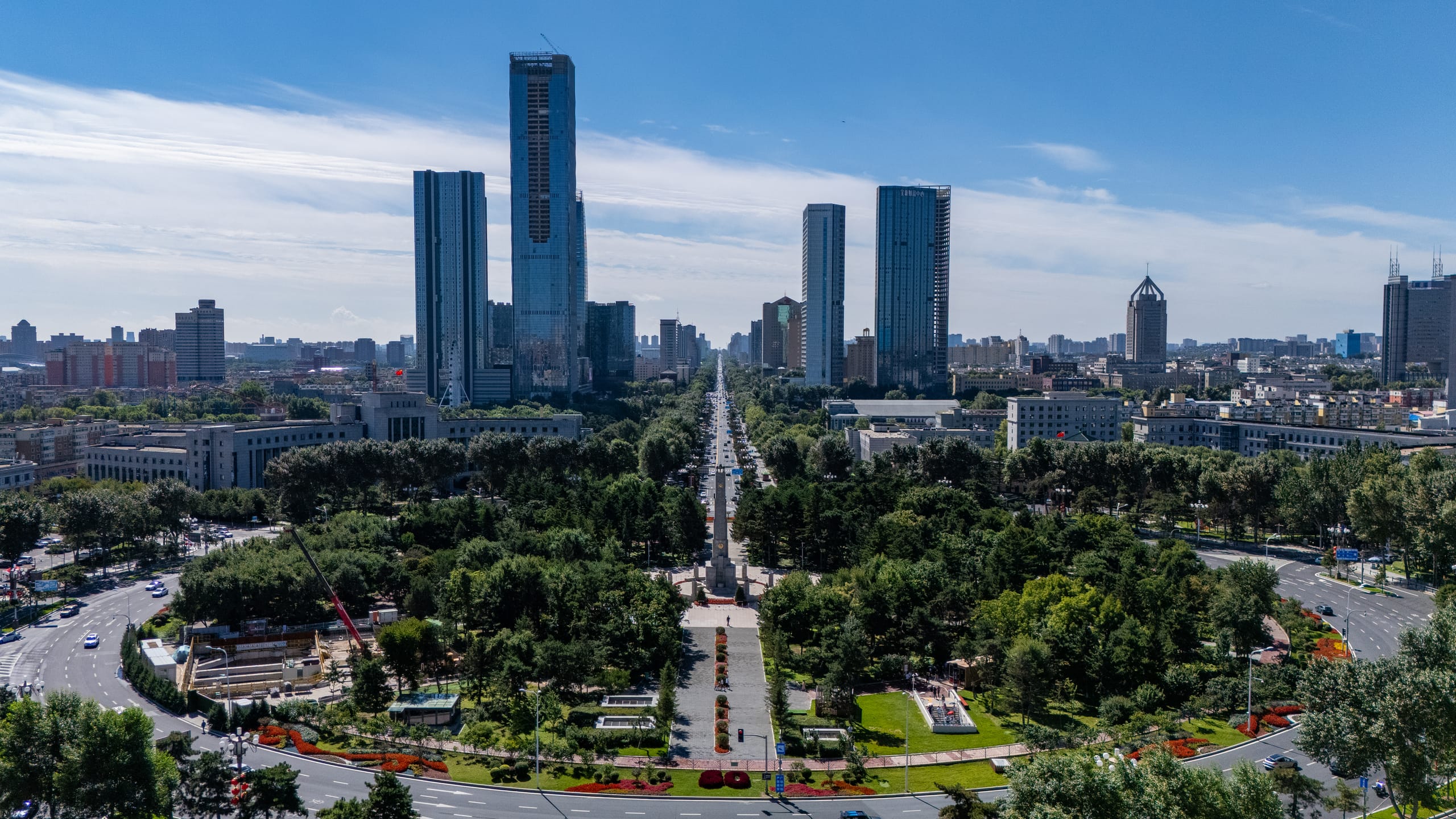 人民广场上方的城市全景，中轴道路穿过绿地通向远处高楼。
